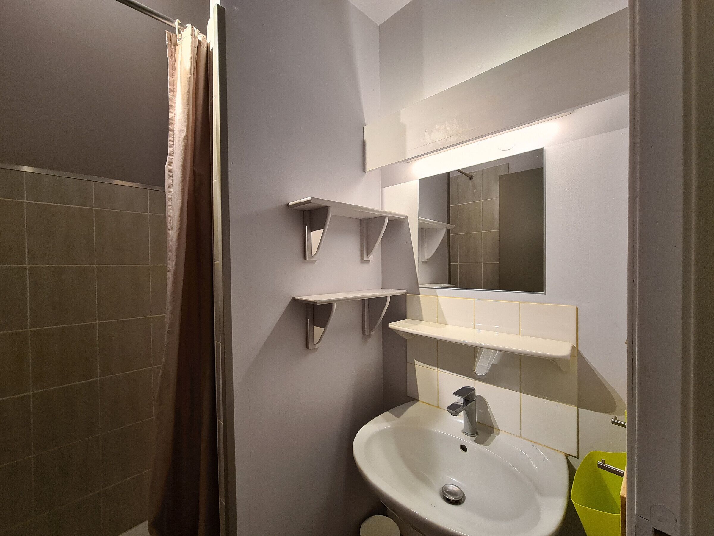 A bathroom with a shower, a sink, and a mirror.