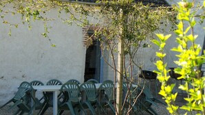 Een terras met een tafel, stoelen, een kleine boom en een bakstenen muur.