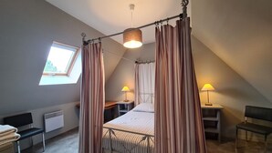 Een slaapkamer met een hemelbed, een dakraam en twee bedlampen.