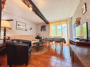A cozy living room with a sofa, a dining table with chairs, a television, and a lamp. - Charming Cottage in Berry: Fireplace, Near Golf & Spa, Sleeps 6, Parking Included (Briantes)