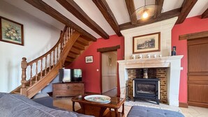A living room with a wooden staircase, a fireplace, a television, and a sofa. - Family Getaway: Heated Pool, Near Zoo de Beauval, Tennis, Garden, 4 Bedrooms (Villentrois-Faverolles-en-Berry)