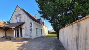 A residential property with a paved driveway, a covered porch, and a large tree providing shade. - Family Getaway: Heated Pool, Near Zoo de Beauval, Tennis, Garden, 4 Bedrooms (Villentrois-Faverolles-en-Berry)