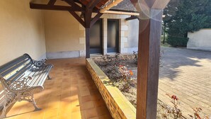 A covered outdoor area with a bench, a tiled floor, and a brick planter with plants. - Family Getaway: Heated Pool, Near Zoo de Beauval, Tennis, Garden, 4 Bedrooms (Villentrois-Faverolles-en-Berry)