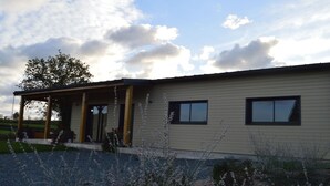 Een gelijkvloers gebouw met een overdekte veranda en een grindpad.