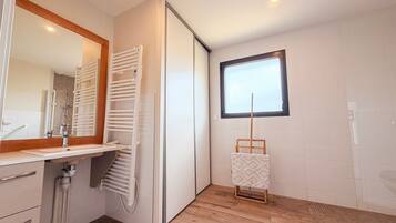 Une salle de bain moderne avec une douche intégrée, un miroir, un porte-serviettes et une fenêtre.