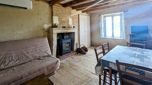 A cozy room with a fireplace, wooden beams, a sofa, a table with chairs, and a television. - Charming Berry Home near Zoo de Beauval & Medieval Loches, Private Parking, Shared Garden (Arpheuilles)