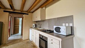 A kitchen with white cabinets, a stove, a microwave, and a sink. - Charming Berry Home near Zoo de Beauval & Medieval Loches, Private Parking, Shared Garden (Arpheuilles)