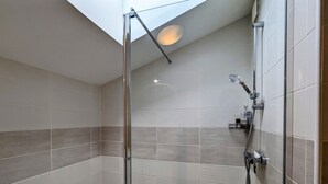 A modern shower with a glass door, a handheld showerhead, and a wall-mounted faucet. - Charming Berry Home near Zoo de Beauval & Medieval Loches, Private Parking, Shared Garden (Arpheuilles)