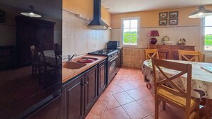 A kitchen with a stove, sink, and window. There is a dining table with chairs.
