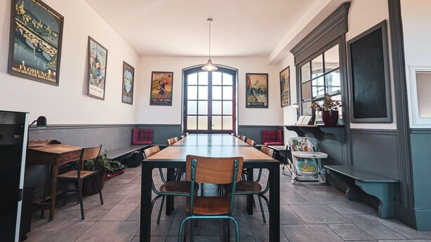 Un comedor con una mesa larga, sillas y un amplio ventanal.
