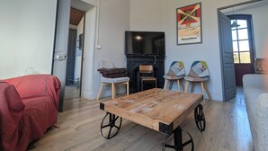 Una sala de estar con una mesa de madera, un sofá rojo, una chimenea y un televisor.