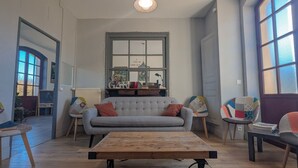 Una sala de estar con un sofá, una mesa de centro, una ventana y una puerta.