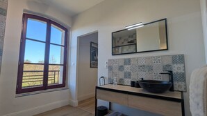 Un baño moderno con un ventanal grande, un lavabo, un espejo y un salpicadero de azulejos.