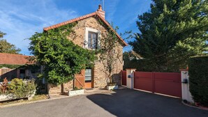 A stone house with a red-tiled roof, a wooden door, and a red gate. - Charming Stone House with Terrace, Kids’ Playground, and Equestrian Space in Scenic Berry (Pérassay)