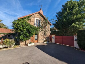 A stone house with a red-tiled roof, a wooden door, and a red gate. - Charming Stone House with Terrace, Kids’ Playground, and Equestrian Space in Scenic Berry (Pérassay)