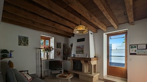 A cozy living room with a fireplace, a sofa, a television, and a window with a view. - Charming Stone House with Terrace, Kids’ Playground, and Equestrian Space in Scenic Berry (Pérassay)