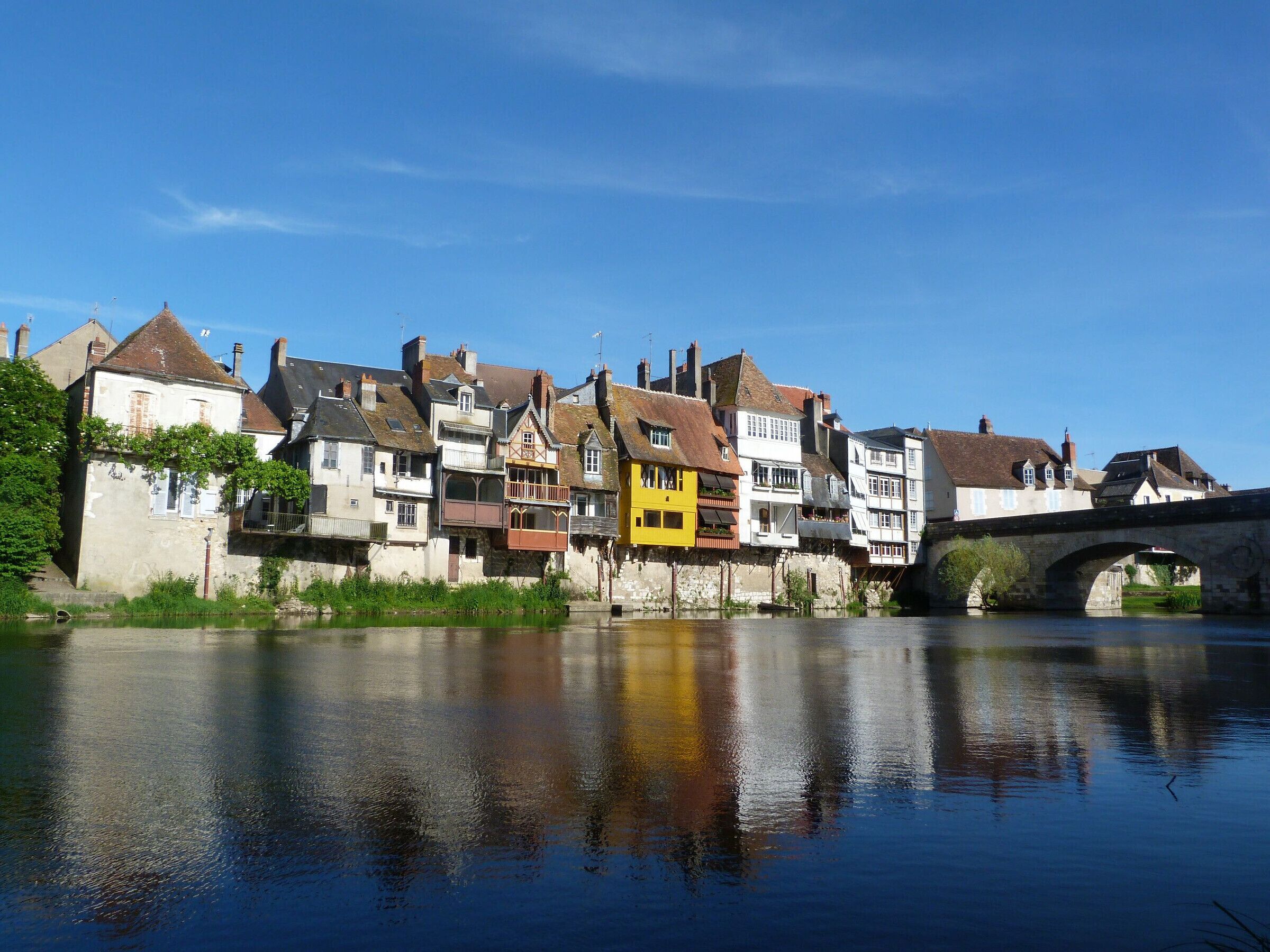 A riverside town with historic buildings and a stone bridge.
