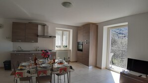 A modern kitchen with a dining area, large windows, and a balcony with a view. - Apartment Azalea with beautiful lake view (Brenzone sul Garda)