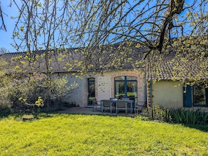 Une maison avec un patio, une cheminée en briques et un jardin.