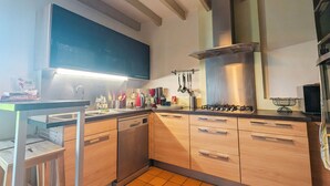 Eine moderne Küche mit Holzausstattung, einer Edelstahl-Dunstabzugshaube und einer gefliesten Rückwand.