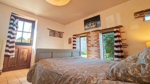 Ein Schlafzimmer mit Bett, Fenster, Tür und Blick ins Freie.