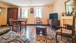 Een gezellige woonkamer met een kamer met een patroon vloer, een eethoek met houten meubels, een televisie en een open haard.