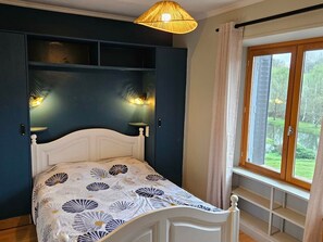 Ein Schlafzimmer mit einem Bett, einem Fenster mit Vorhängen und Wandleuchten.