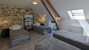 A bedroom with a sloped ceiling, exposed wooden beams, a stone wall, and a skylight. - Countryside Retreat with Private Garden - Perfect for Family Relaxation! (Pouligny-Notre-Dame)