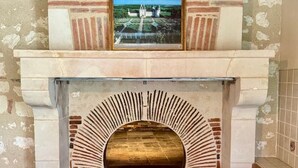 A brick fireplace with a decorative arch and a framed picture above it. - Family & Friends Retreat: Near Loire Castles, ZooParc de Beauval, Spacious Garden, Sleeps 12 (Vicq-sur-Nahon)