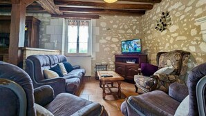 A cozy living room with a fireplace, a television, and a stone wall. - Family & Friends Retreat: Near Loire Castles, ZooParc de Beauval, Spacious Garden, Sleeps 12 (Vicq-sur-Nahon)