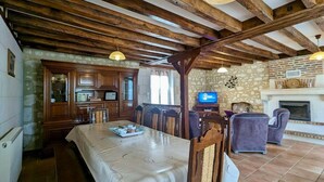 A rustic interior with exposed wooden beams, a stone fireplace, and a dining area with a table set for two. - Family & Friends Retreat: Near Loire Castles, ZooParc de Beauval, Spacious Garden, Sleeps 12 (Vicq-sur-Nahon)