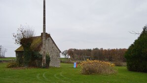 A stone building with a chimney, a swing set, and a grassy field.