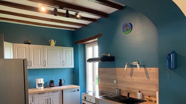 A modern kitchen with white cabinets, a stainless steel refrigerator, a coffee maker, and a wooden countertop.