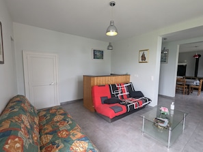 Ein Wohnzimmer mit einer Couch, einem Glastisch und einem Holzschrank.