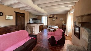 A spacious living area with a kitchen in the background, a fireplace, and a dining area. - Peaceful cottage in Berry, family ideal (Sainte-Fauste)
