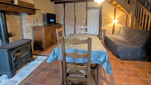 Ein rustikaler Raum mit Holztisch, Stühlen, einer Couch, einem Fernseher auf einem Schrank und einem Kamin.