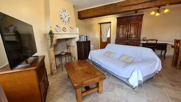 Un salon chaleureux avec un canapé, un banc en bois, une télévision, une cheminée et des meubles en bois.