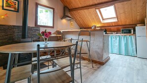 Et køkken med træloft, spiseplads med bord og stole, mikroovn og køleskab.