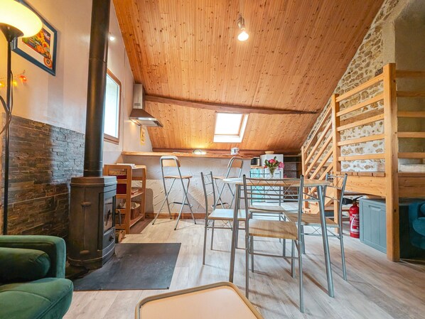 A cozy loft-style room with a wooden ceiling, a stone wall, and a kitchen area with a sink and stove. - Charming Cottage with Heated Pool, Private Garden, Near Creuse River and Historic Villages (Le Menoux)