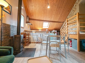 Un acogedor espacio tipo loft con techo de madera, pared de piedra y área de cocina con pileta y estufa.