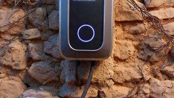 A portable charging station with a digital display, connected to a cable, placed on a rocky surface.
