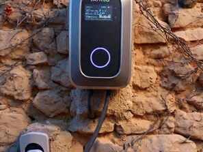 Una estación de carga portátil con pantalla digital, conectada a un cable, sobre una superficie rocosa.