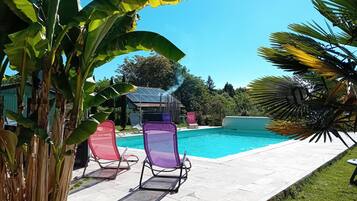 A swimming pool with lounge chairs, surrounded by tropical plants.