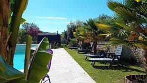 A poolside area with lounge chairs and a pathway leading to a building. - Cozy Renovated Forge with Sauna, Shared Pool & Nearby Attractions (Le Menoux)