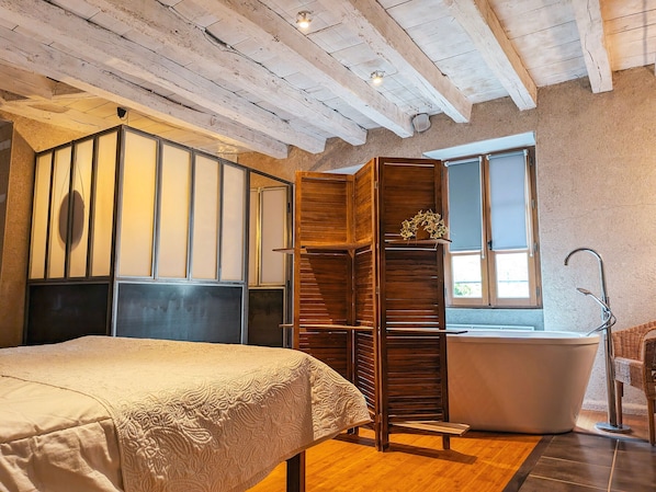 Une chambre à coucher avec un lit, une armoire en bois, une baignoire et une fenêtre.