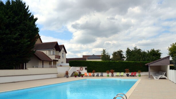 Une piscine rectangulaire avec un escalier en métal, entourée d’une terrasse carrelée.