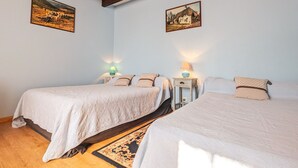 Een kamer met twee eenpersoonsbedden, houten balken in het plafond en twee wandlampen.