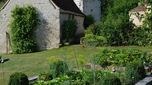 A stone building with a sloped roof, surrounded by lush greenery and a well-maintained garden. - Charming Nature Retreat with King Bed, Private Terrace, and Shared Pool in the Brenne Park (Chalais)