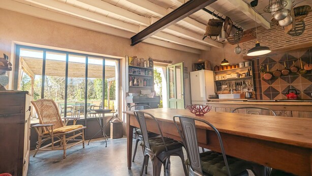 Una cocina amplia con una mesa y sillas de madera, un refrigerador y diversos utensilios de cocina.