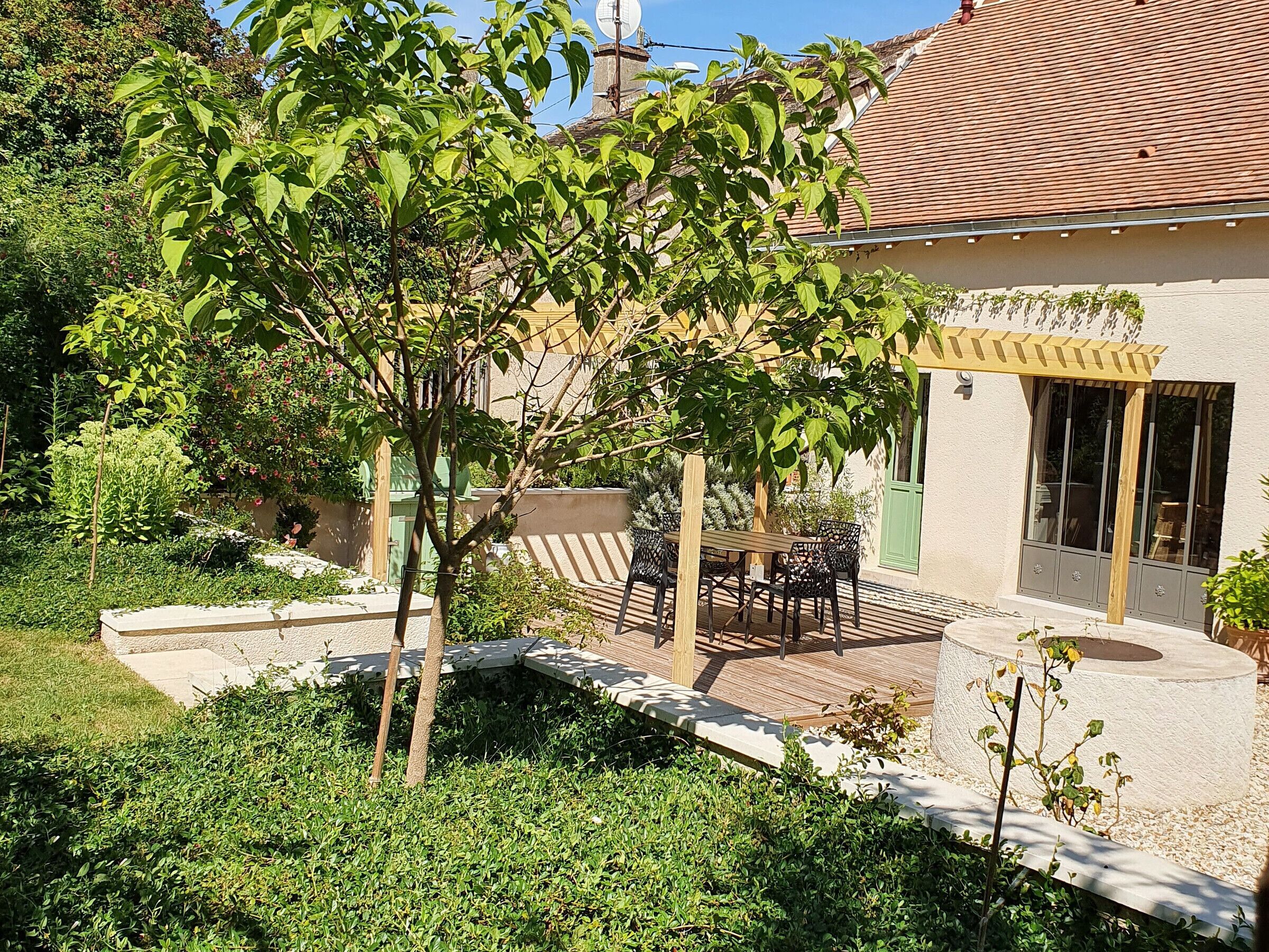 A patio with outdoor furniture, a pergola, and a small tree.